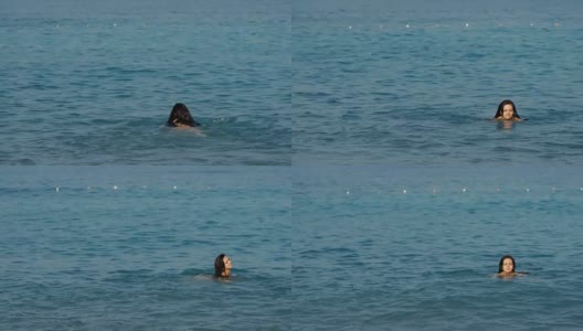 一个留着长发的年轻女子在阳光灿烂的日子里在海里游泳高清在线视频素材下载