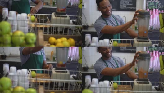 一个在果汁吧工作的黑人，把水果加到果汁机里做成果汁高清在线视频素材下载