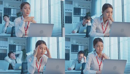 精疲力竭的亚洲生病的企业女工在办公室的桌子上工作。员工在工作到很晚，在工作场所的电脑桌上过度工作，会感到疲惫和头痛。高清在线视频素材下载