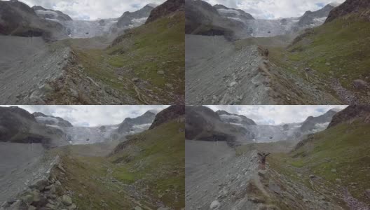 一名年轻男子在瑞士山脊上伸开双臂站立的无人机照片高清在线视频素材下载