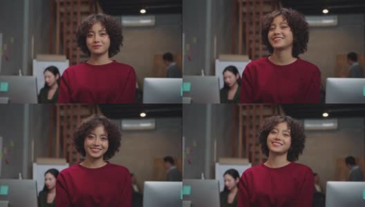 迷人的亚洲女商人微笑着看着相机，一个积极的，满意的，愉快的表情享受在一个现代的办公室成功摆姿势。高清在线视频素材下载