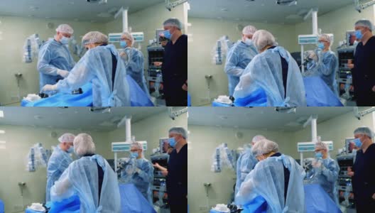 手术室里的一组医生。一群身穿蓝色制服的医务人员在医院里用手术设备进行手术。高清在线视频素材下载