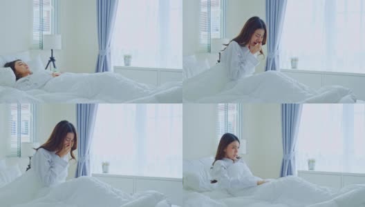 亚洲美丽生病的女孩在睡衣起床在卧室。有吸引力的年轻女子感觉不好醒来后在床上和咳嗽清晨在家里。健康care-lifestyles概念。高清在线视频素材下载