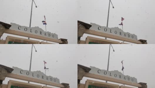 前景中的科罗拉多信息标志，作为美国国旗和科罗拉多州旗在韦尔垭口的风中飘扬，在一个多雪、多雾的日子里，沿着70号州际公路的科罗拉多山山顶的休息站高清在线视频素材下载