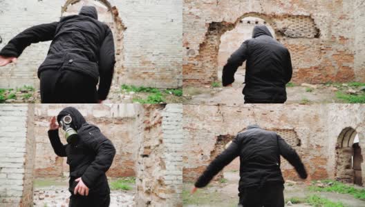 一个戴着防毒面具穿着黑色衣服的人跑在一座废弃的废墟上。跟踪者概念，核化学战争幸存者。缓慢的运动。高清在线视频素材下载