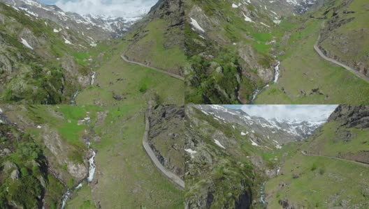 空中:飞越高山峡谷，风景如画的瀑布，雪山山脉和戏剧性的道路高清在线视频素材下载
