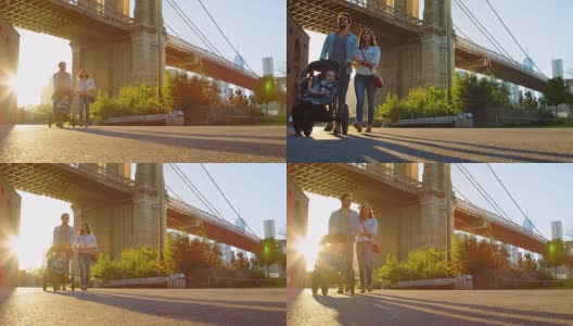 一个年轻的家庭推着婴儿车在曼哈顿的桥下散步高清在线视频素材下载