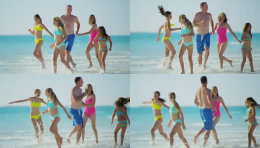 一个白人家庭穿着五颜六色的泳衣赤脚在海滩上高清在线视频素材下载