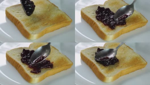 人们用金属勺把蓝莓果酱涂在烤面包上。高清在线视频素材下载