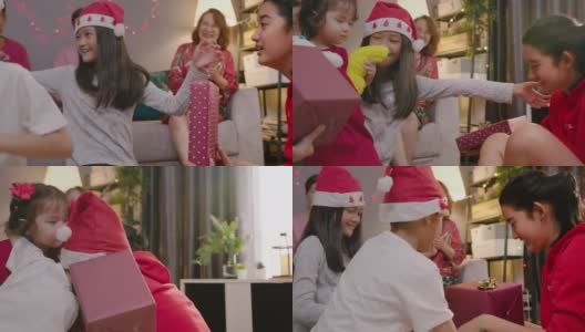 亚洲少女惊喜礼物盒给她可爱的哥哥和妹妹，而庆祝她的家人在圣诞节假期在家里的客厅。四个兄弟姐妹拥抱和微笑。高清在线视频素材下载