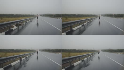 运动员在雨中跑马拉松的路上渐渐远去，眼前的景象。运动员在雷雨中沿着公路奔跑高清在线视频素材下载
