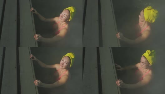 近距离的白人妇女在热盐水矿泉水浴在一个传统的温泉与软魔术粉红色照明蒸汽户外游泳。地热温泉高清在线视频素材下载