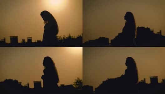 年轻苗条的女子在傍晚散步，背景是城市风景，映衬着太阳的轮廓高清在线视频素材下载