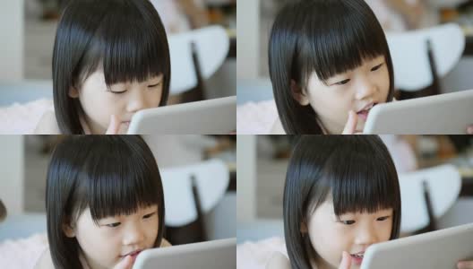 学龄前的亚洲女孩在家里使用数字平板电脑高清在线视频素材下载