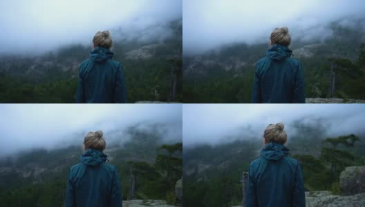 在云天的慢镜头中，年轻女子站在山上的视点上高清在线视频素材下载