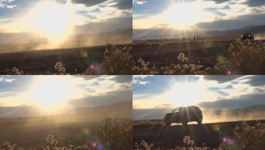 慢镜头:黑色SUV行驶在土路上，扬起金色夕阳的尘土高清在线视频素材下载