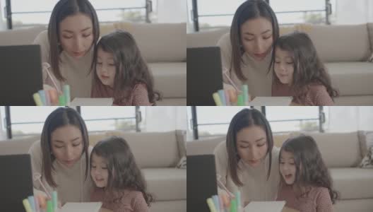 亚洲母亲帮助学龄前的女儿女孩在家里使用笔记本电脑电子学习，放大在线虚拟课堂，家庭教育，新常态的概念高清在线视频素材下载