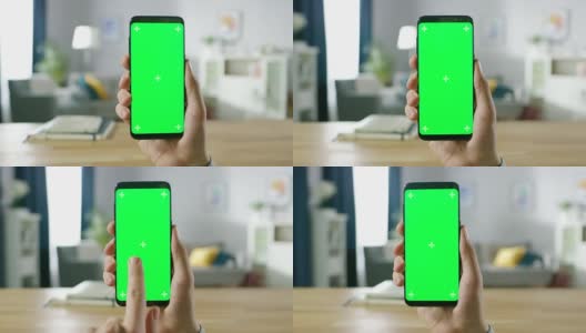 一个男人的特写持有绿色模拟屏幕智能手机和使用触摸屏手势。触摸手机色度键屏幕。在背景舒适的家庭气氛。高清在线视频素材下载