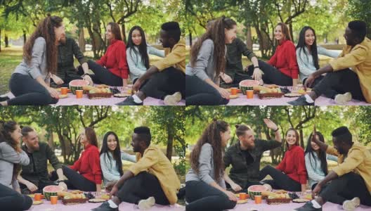 欢乐的朋友非洲裔美国人和白人在城市公园野餐时击掌的慢动作。友谊，健康的生活方式和联系的概念。高清在线视频素材下载