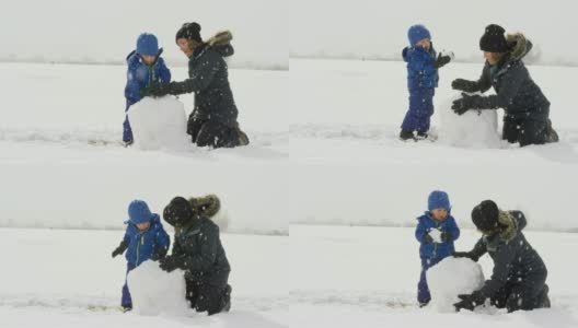 3岁的白人男孩和他的白人母亲在她30多岁(都穿着冬天的衣服)一起堆雪人在一个下雪，阴天高清在线视频素材下载