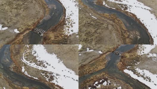 从上到下无人机拍摄的溪流蜿蜒穿过正在融化的草地高清在线视频素材下载
