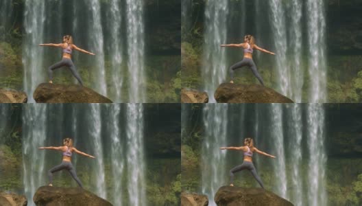 苗条的女孩在圆形岩石上对着瀑布摆姿势高清在线视频素材下载