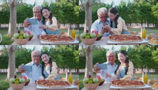 亚洲退休的爷爷和漂亮的孙女在家里的花园里享受着披萨。有家庭观念的退休老人快乐生活。高清在线视频素材下载