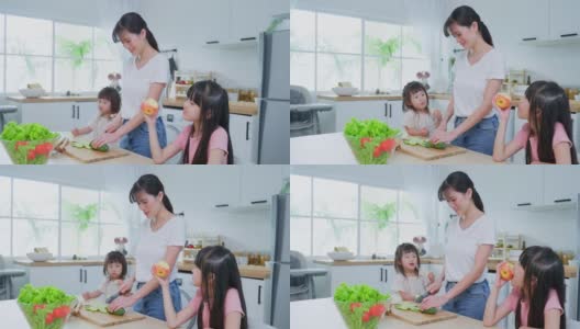 亚洲幸福的家庭，母亲花时间与年幼的女儿在厨房。可爱美丽的父母妈妈和小妹妹可爱的女孩孩子感到高兴，在家享受吃苹果健康。健康食品的概念高清在线视频素材下载