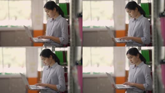 亚洲大学图书馆，一名亚洲女子正在图书馆用平板电脑上网。高清在线视频素材下载