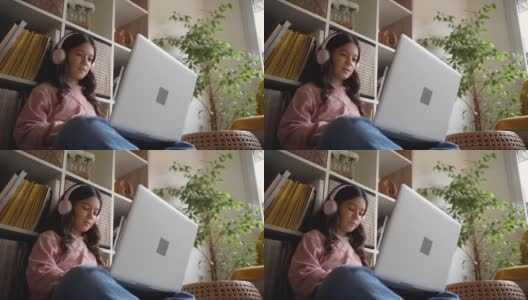 坐在地板上，可爱的女生，在笔记本电脑上做着教育科目的小测验高清在线视频素材下载