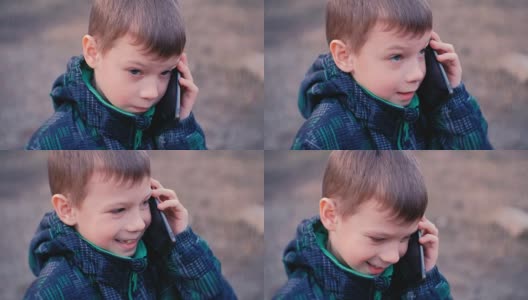 男孩在公园里用手机说话，笑着说。正面，特写。高清在线视频素材下载