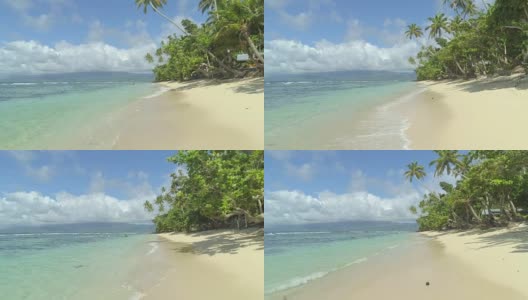 低角度视角:泡沫波浪翻滚向斐济岛的沙海岸线。高清在线视频素材下载