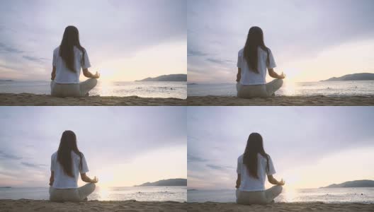 日出时，年轻女子在海滩上练习瑜伽。高清在线视频素材下载