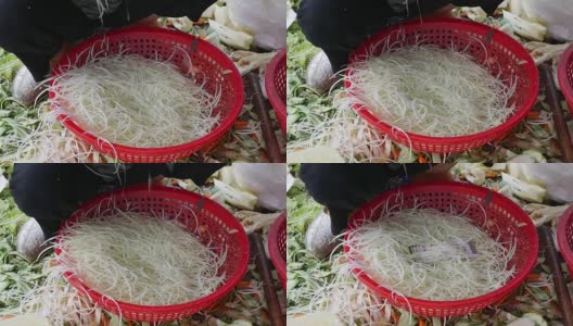 在当地市场，一名妇女将青木木瓜切成丝，放在篮子里做沙拉。特写镜头高清在线视频素材下载