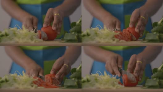 近距离拍摄的女人的手切西红柿在木砧板上的健康食物在桌子上。高清在线视频素材下载