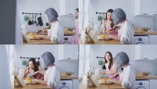 亚洲可爱的家庭，年轻的女儿看着老妈妈在厨房做饭。漂亮女性享受与年长的妈妈在家里餐桌上烤牛角面包的闲暇时光。活动的关系。高清在线视频素材下载