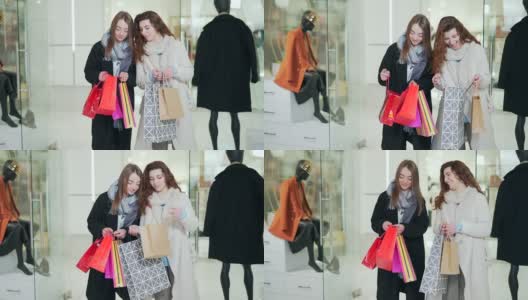 两个时尚的女孩在购物中心的服装店选购礼品袋。年轻成人快乐开朗的女性高清在线视频素材下载