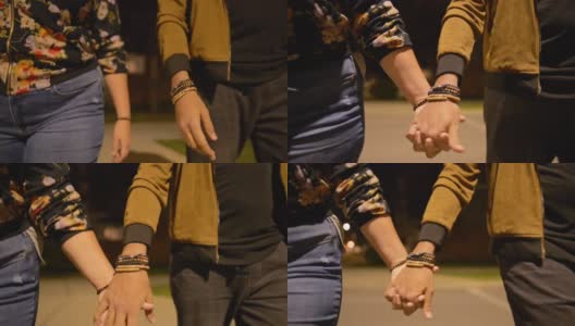 年轻的夫妇在晚上手牵着手一起在外面散步高清在线视频素材下载
