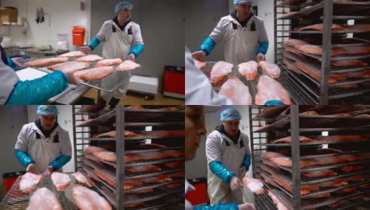 工厂里，一个工人把鲑鱼片放进烤箱里熏鱼高清在线视频素材下载