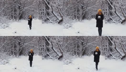 一个快乐的女孩走过冬天的森林，微笑，有一个好心情，玩雪，扔雪球高清在线视频素材下载