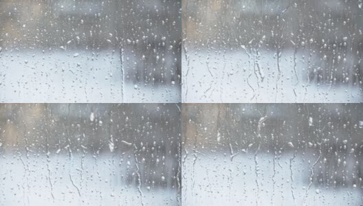 水滴飞溅到玻璃上。雨天的窗户。用大滴的水或雨浸湿玻璃杯。在大雨期间水滴在一个清晰的玻璃表面的视频。滴水高清在线视频素材下载