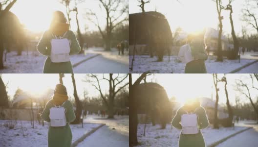 罕见的景象，一个女人走过冬天的公园，用耳机听着音乐，回头看高清在线视频素材下载
