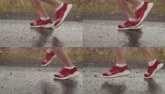 男子铁人三项运动员的腿穿着红色运动鞋在下雨时在沥青上奔跑，侧视图，特写。运动员在雷雨中沿路奔跑高清在线视频素材下载
