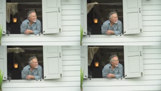 快乐的亚洲老人在窗口在家里高清在线视频素材下载