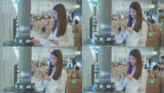 年轻的亚洲女子在机场候机楼充电站为她的手机充电高清在线视频素材下载