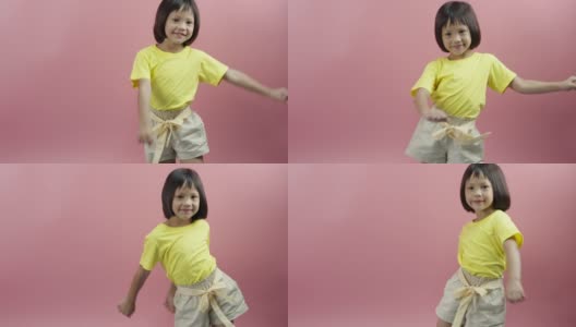 小女孩听着音乐，在粉红色的背景上跳舞。高清在线视频素材下载