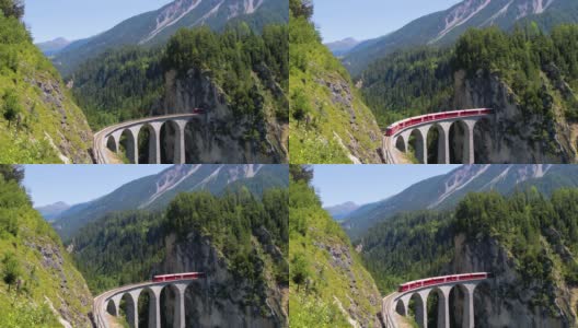 火车在美丽的瑞士山脉中间行驶。列车正驶向一座进入山区的大桥，背景是美丽的风景——4K无人机鸟瞰图高清在线视频素材下载