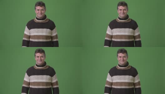 成熟英俊的男人穿着高领毛衣对绿色的背景高清在线视频素材下载