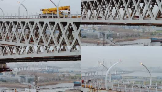 近景航拍位于桁架桥的大型现代汽车起重机，以城市景观为背景高清在线视频素材下载