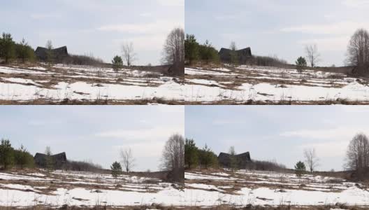 被遗弃和摧毁的俄罗斯村庄小屋分别矗立在雪地里，春天的时候。高清在线视频素材下载